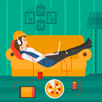 Woman lying on sofa with many gadgets.