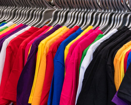 Various colored T-shirts on hangers
