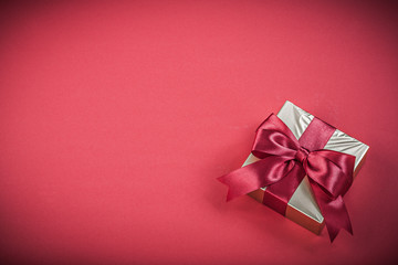 Gift container with tied ribbon on red background holidays conce