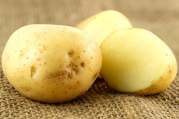 Macro of whole unpeeled potatoe next to cut pieces