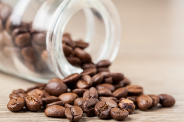 Coffee beans and glass jar on wooden background.. Selective focus.