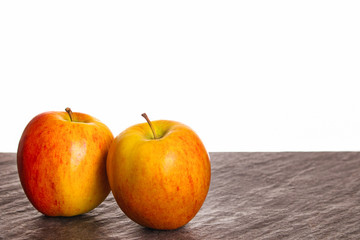 Zwei Äpfel auf Granittischplatte vor weßem Hintergrund