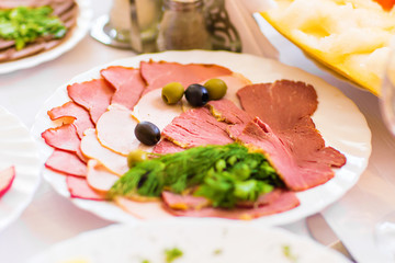 Fototapeta na wymiar Serving of delicious smoked ham and appetizers displayed on a plate on a buffet at a party or reception