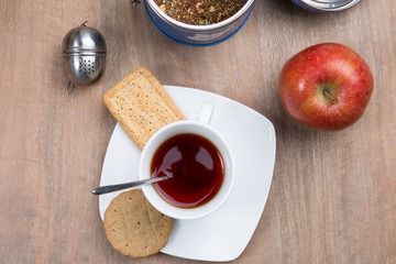 Cup of tea and traditional french cake under wooden background