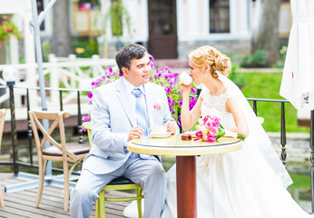 Bride and groom drinking coffee at an outdoor cafe