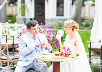 Bride and groom drinking coffee at an outdoor cafe