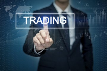Obraz premium Businessman hand touching TRADING button on virtual screen
