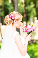 Obraz premium Beautiful bride with wedding bouquet of flowers outdoors in green park