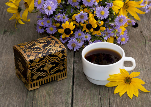 coffee, casket and bouquet of beautiful wild flowers, on a woode