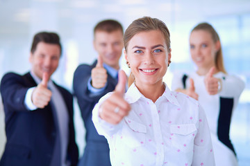 Happy business team showing thumbs up in office