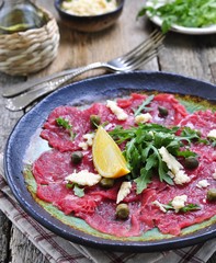 beef carpaccio with capers, parmesan, arugula, lemon and olive oil.