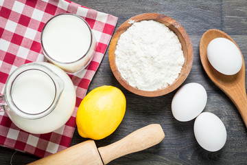 ingredients for making pancakes or cake - flour, egg, butter, milk, lemon on the old wooden background. top view. rustic or rural style. background with free text space. Ingredients for the dough