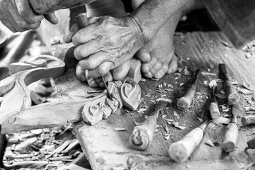 Hand of carver carving wood in black and white color tone