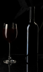Elegant wine glass and a wine bottle in black background