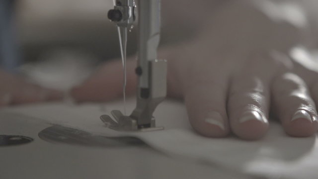 white woman works seamstress sewing stitch on the sewing machine in slow motion. macro