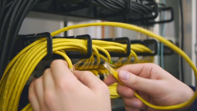 Hands replace yellow ethernet cable