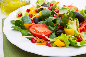 mixed salad with tomatoes in white plate on wood table