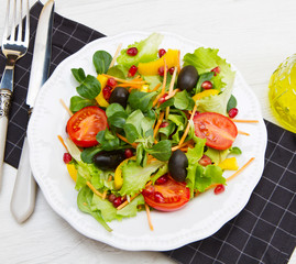 mixed salad with tomatoes in white plate on wood table