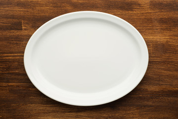 Empty white plate on wooden table
