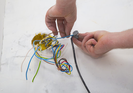 Electrician hands connecting wires with electrical cable during residential renovation