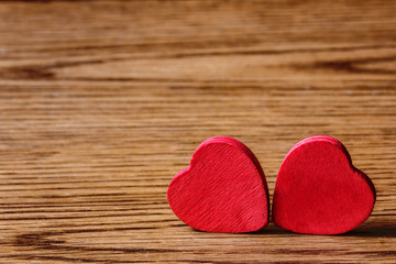 Two wooden hearts on wooden surface.