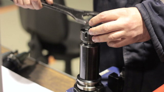 Close-up mechanical industrial worker measuring detail in tool workshop.