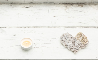 small candle and white paper heart on old window