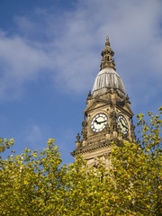 Fototapeta na wymiar The clock tower of the town hall in Bolton, Lancashire, standing proud above the leafy tree tops in Victoria Square.
