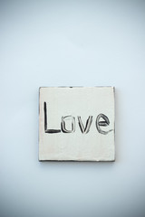 Black love text on handmade white jewellery closeup, background