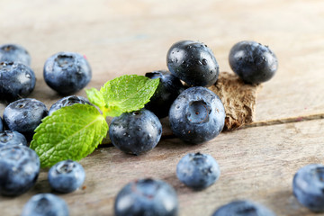 Tasty ripe blueberries with green leaves on wooden table close up