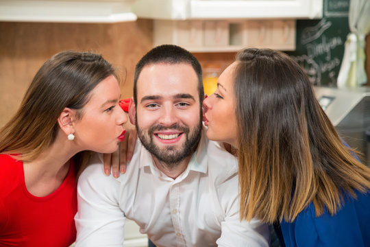 Happy man being kissed by two girls.