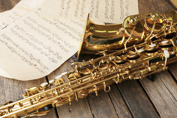Obraz premium Beautiful golden saxophone with musical notes on wooden background, close up