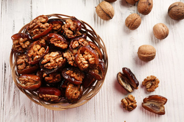Walnut and date fruit in plate on wooden table, close-up