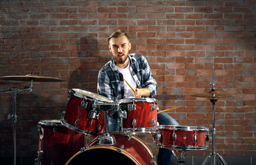 Fototapeta na wymiar Musician playing the drums on brick wall background