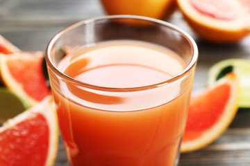Glass of grapefruit juice and fresh fruits on wooden background