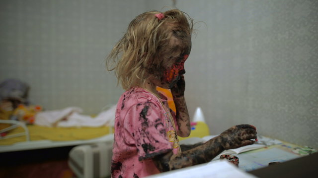 A small girl with paint all over her face.