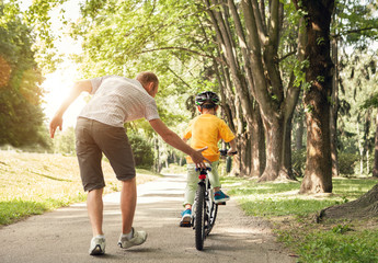 Father learn his little son to ride a bicycle
