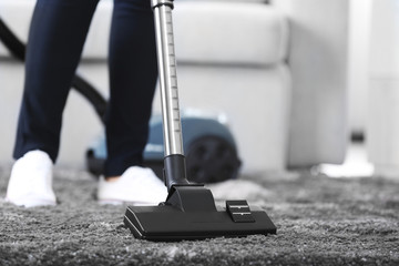 Cleaning concept - woman cleaning the room with carpet sweeper, close up