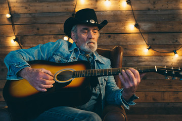 Guitar playing senior country and western musician with beard si