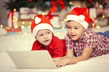 Two cute small brothers using laptop on Christmas decoration background