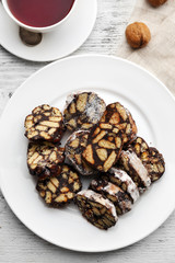 Chocolate salami in a plate over wooden background, close up