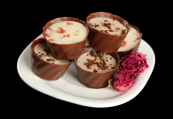Assorted chocolate candies on white plate over black background