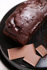 Chocolate cake with icing on baking dish over white table