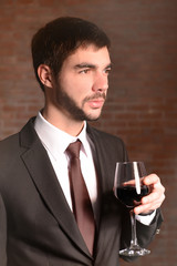 Man holding red wine in glass on brick wall background