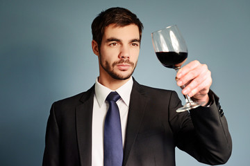 Man looking at the glass of red wine on blue background