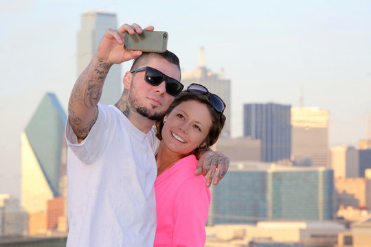 Young couple taking selfie portrait against Dallas Texas skyline