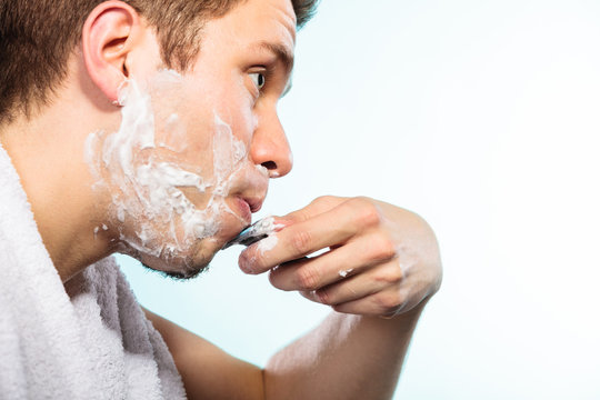 Man shaving using razor with cream foam.