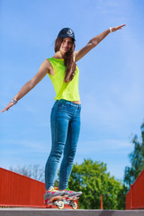 Teen girl skater riding skateboard on street.