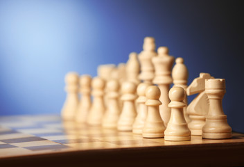 Chess pieces and game board on blurred background