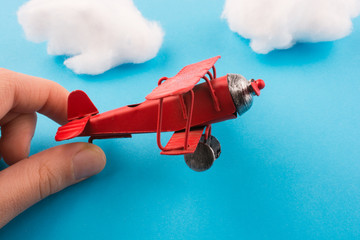 Toy airplane in hand and clouds
